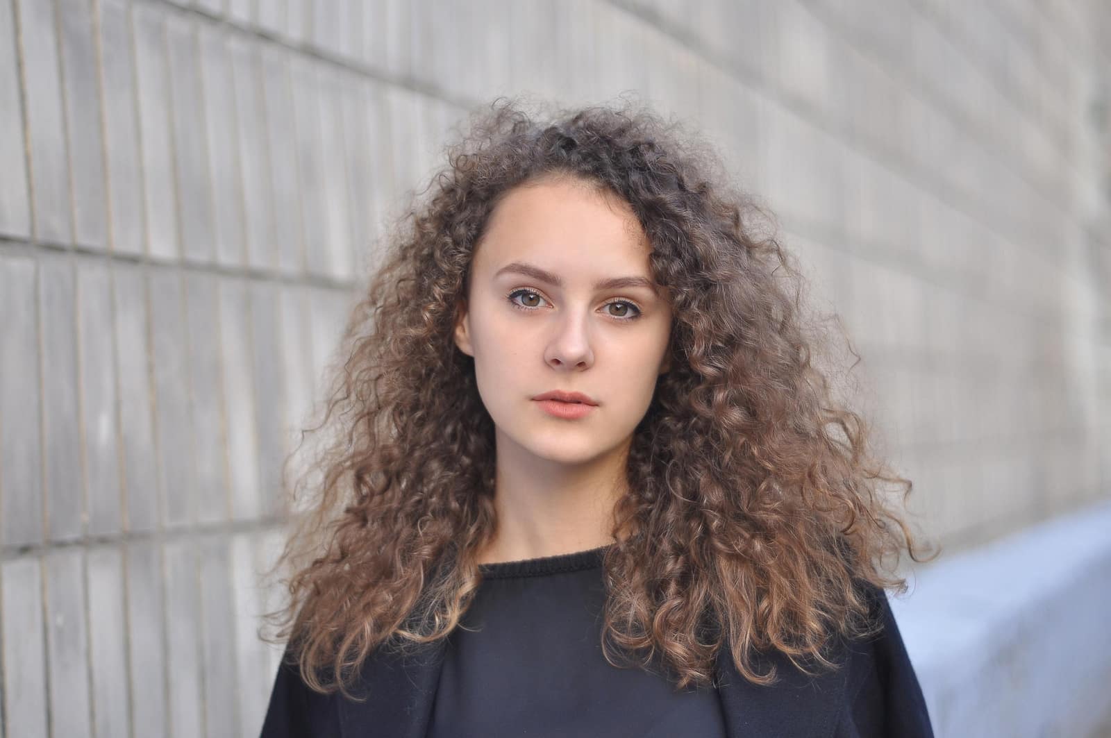 Femme aux cheveux bouclés en train de laver ses cheveux avec un shampoing doux