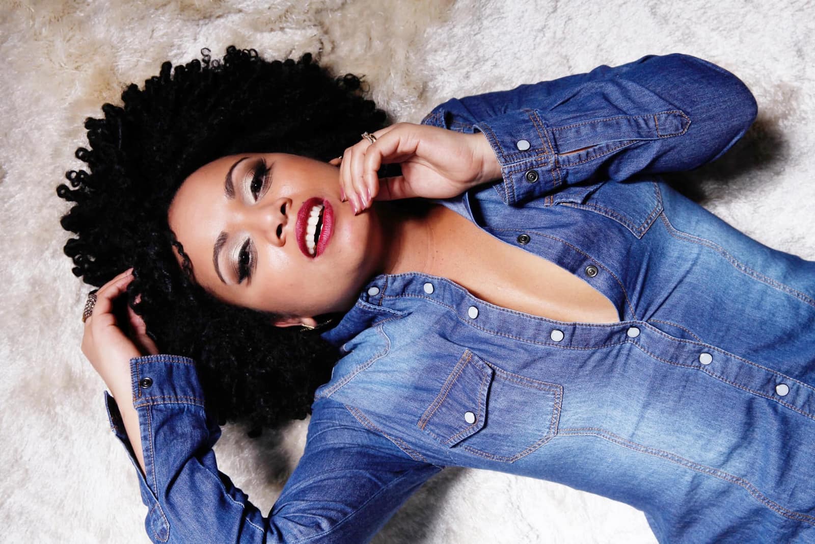 Femme aux cheveux bouclés lisant la composition d’un produit capillaire